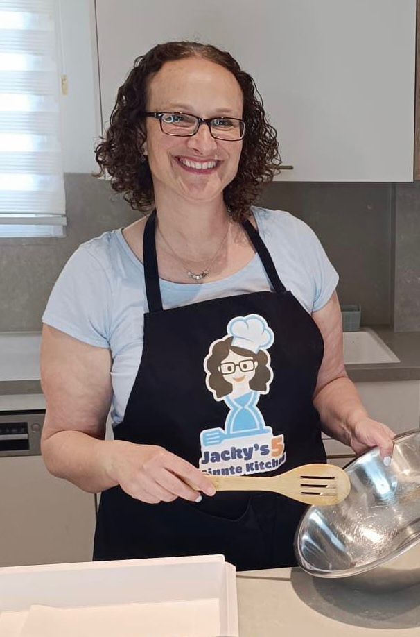 Jacky smiling in her kitchen while holding a wooden spoon and mixing bowl