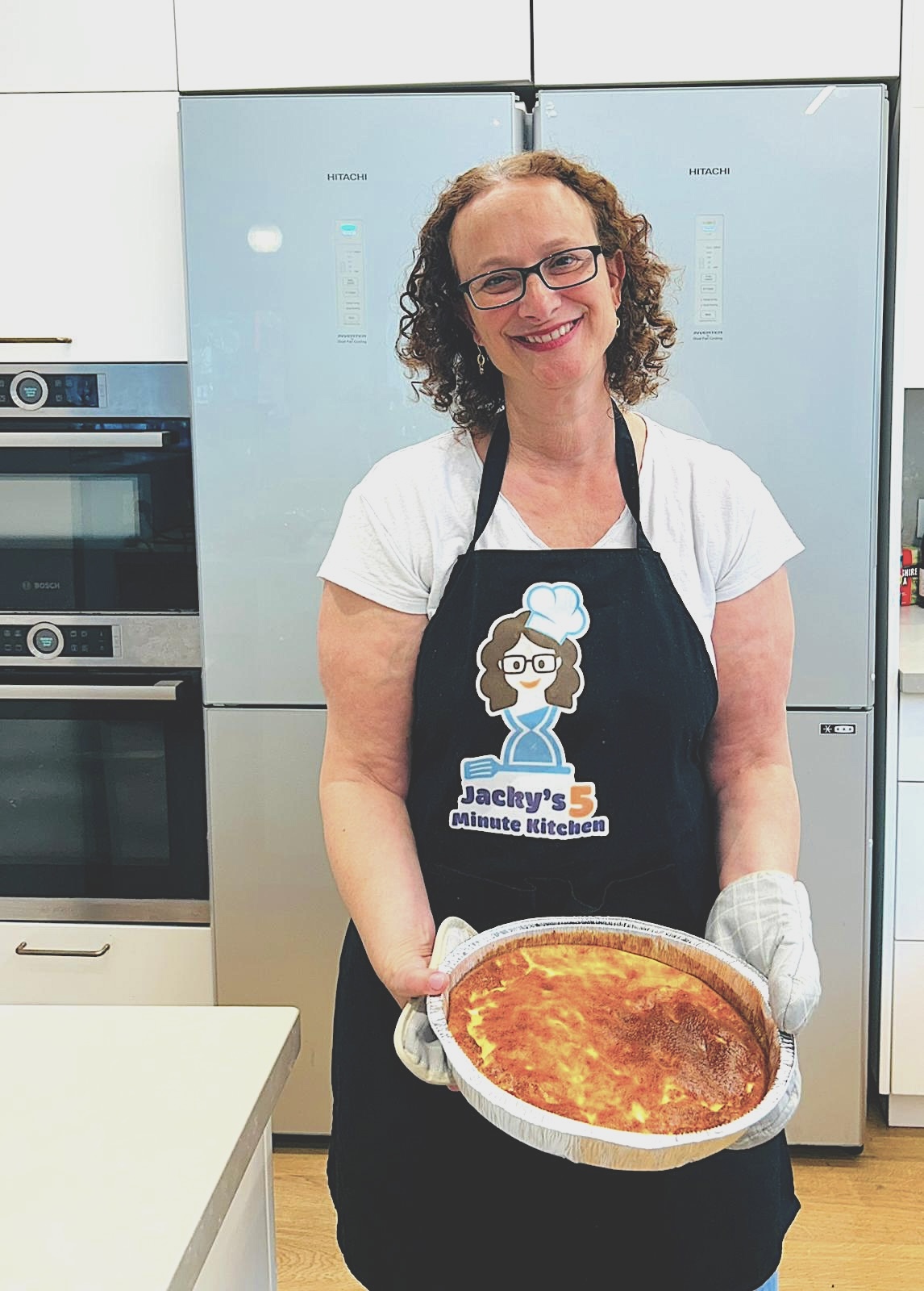 Jacky smiling in her kitchen while holding a homemade quiche